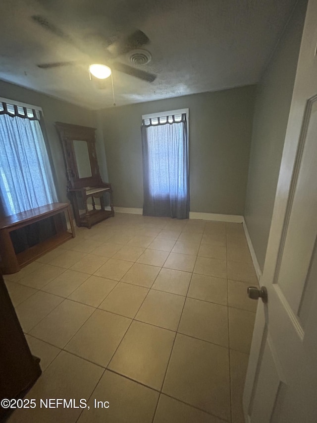 empty room featuring visible vents, ceiling fan, baseboards, and tile patterned floors