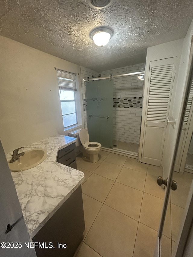 full bath with a stall shower, toilet, tile patterned floors, a textured ceiling, and vanity