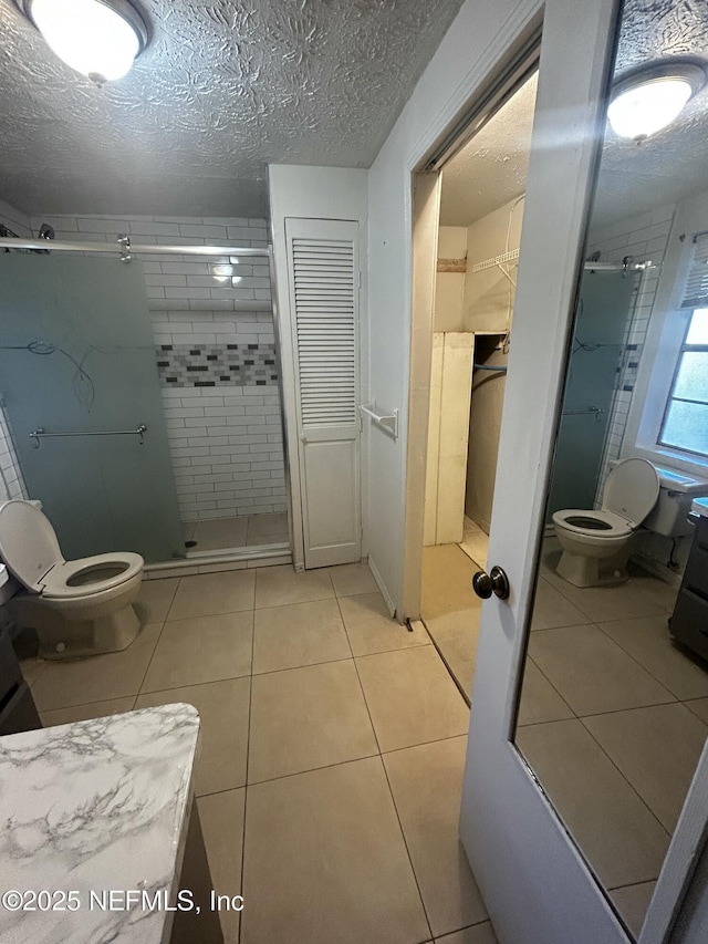 bathroom with toilet, tile patterned flooring, a textured ceiling, and a shower stall