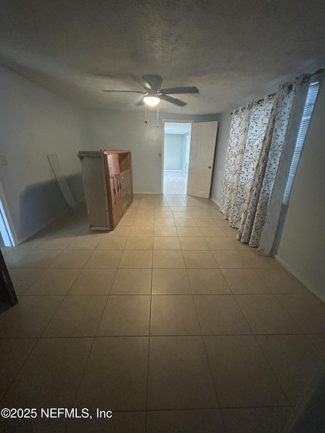 tiled empty room with a ceiling fan and a textured ceiling