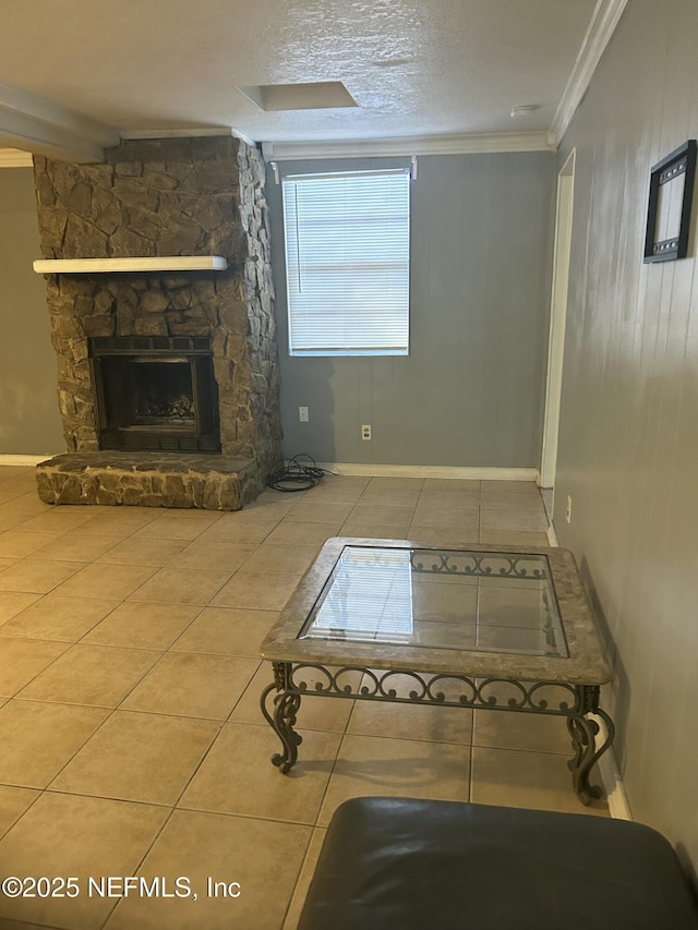 unfurnished living room featuring ornamental molding, tile patterned flooring, a stone fireplace, and a textured ceiling