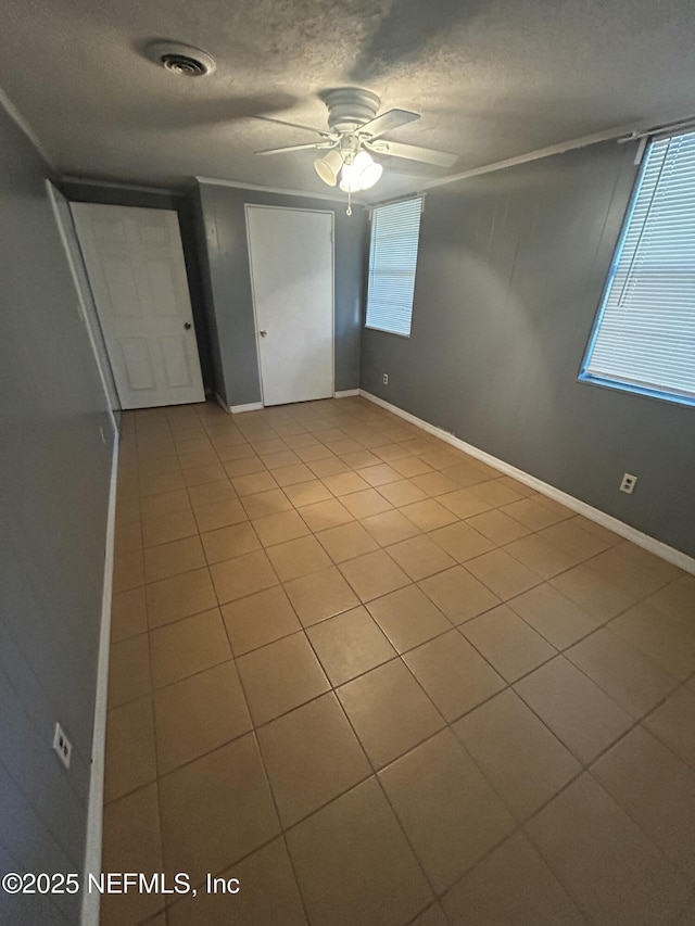 interior space featuring a textured ceiling, ceiling fan, visible vents, and baseboards