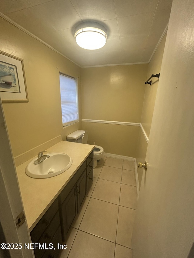 bathroom featuring toilet, ornamental molding, vanity, tile patterned flooring, and baseboards