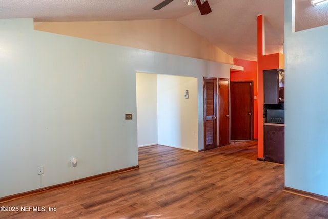 spare room featuring lofted ceiling, ceiling fan, wood finished floors, and baseboards