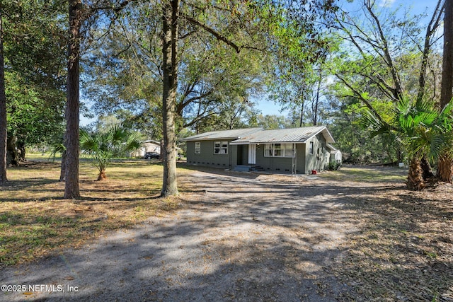 view of front of property featuring driveway and metal roof