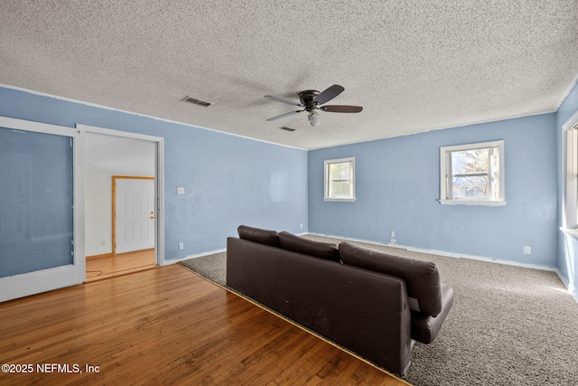 living area with a textured ceiling, wood finished floors, a ceiling fan, and baseboards