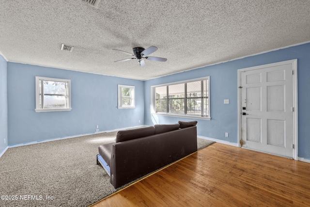 living area featuring baseboards, visible vents, ceiling fan, and wood finished floors