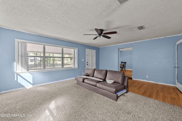 living area with a textured ceiling, a ceiling fan, visible vents, and baseboards