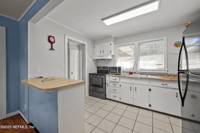 kitchen featuring under cabinet range hood, a sink, white cabinets, freestanding refrigerator, and stainless steel electric stove