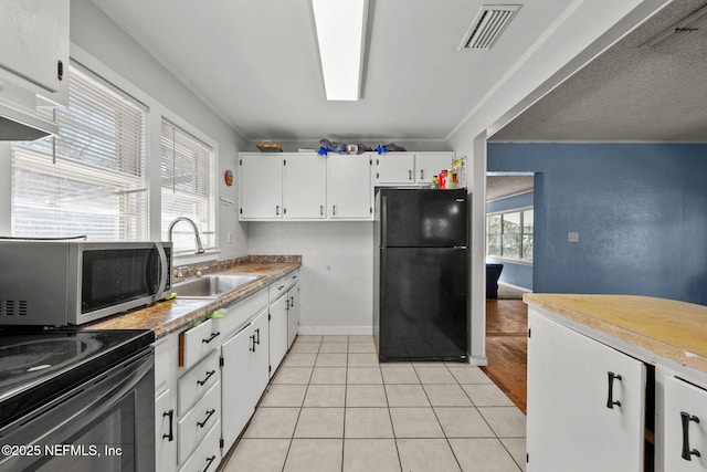 kitchen with visible vents, stainless steel microwave, freestanding refrigerator, white cabinets, and a sink