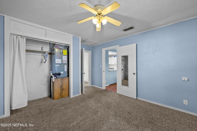 unfurnished bedroom featuring a textured ceiling, carpet floors, visible vents, a closet, and heating unit