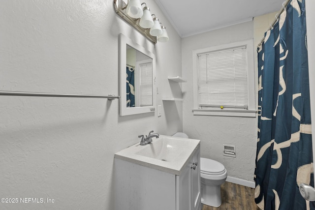 bathroom featuring a textured wall, toilet, wood finished floors, vanity, and ornamental molding