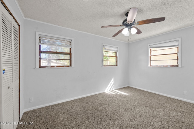 unfurnished bedroom with a textured ceiling, carpet flooring, baseboards, ornamental molding, and a closet