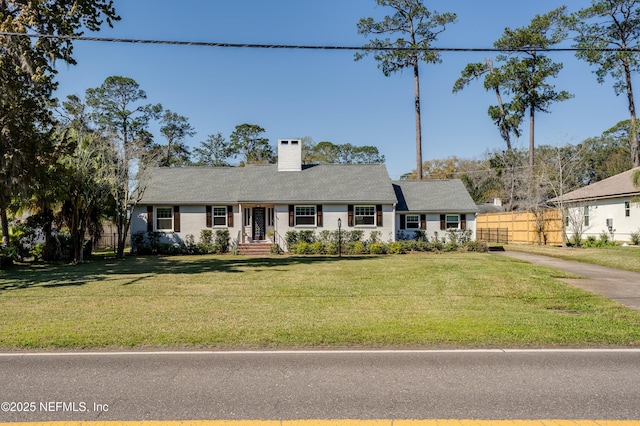 view of front of house with a chimney, fence, and a front yard