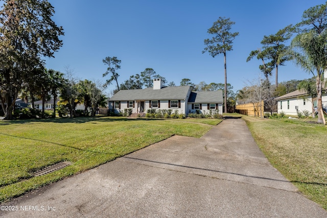 view of front of property with a front lawn, a chimney, and fence