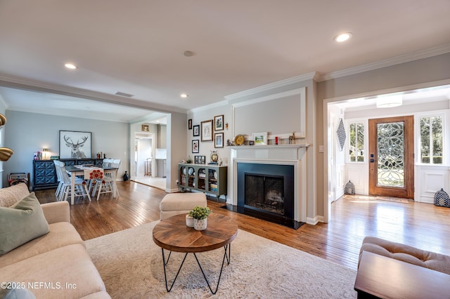 living room with ornamental molding, recessed lighting, and wood finished floors