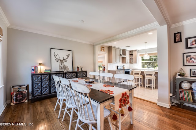 dining area with wood-type flooring, ornamental molding, and baseboards