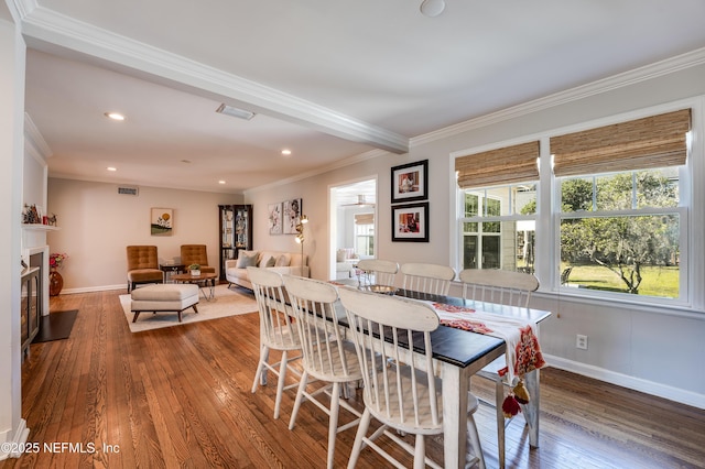 dining room featuring baseboards, a fireplace, wood-type flooring, and crown molding