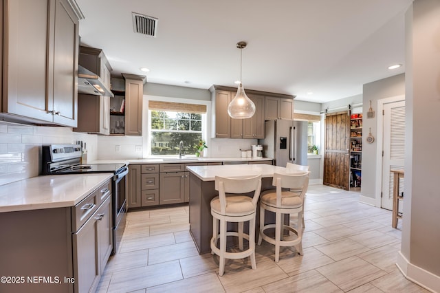 kitchen featuring a barn door, visible vents, decorative backsplash, appliances with stainless steel finishes, and a sink