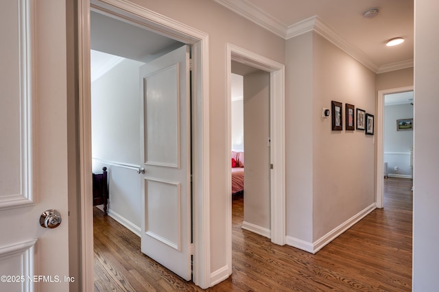 corridor with crown molding, baseboards, and wood finished floors