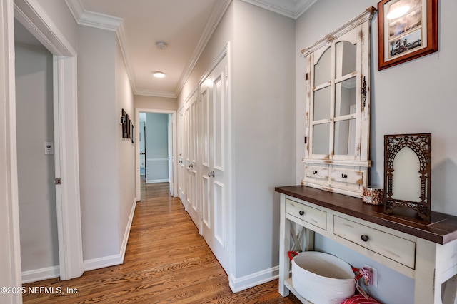 hallway with baseboards, ornamental molding, and wood finished floors