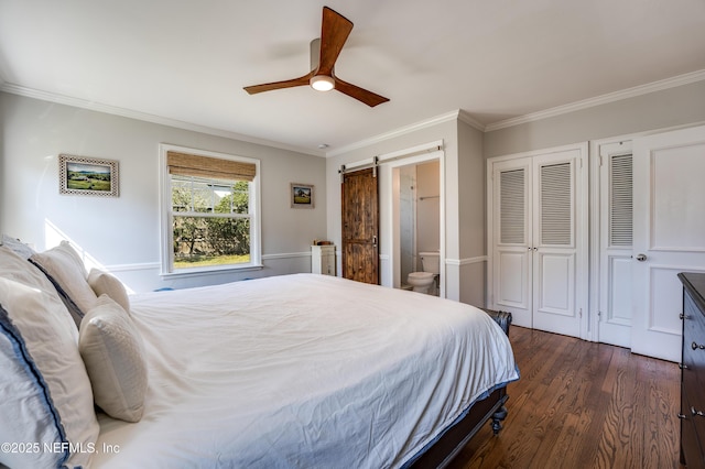 bedroom with ornamental molding, a barn door, dark wood-style flooring, and ensuite bath