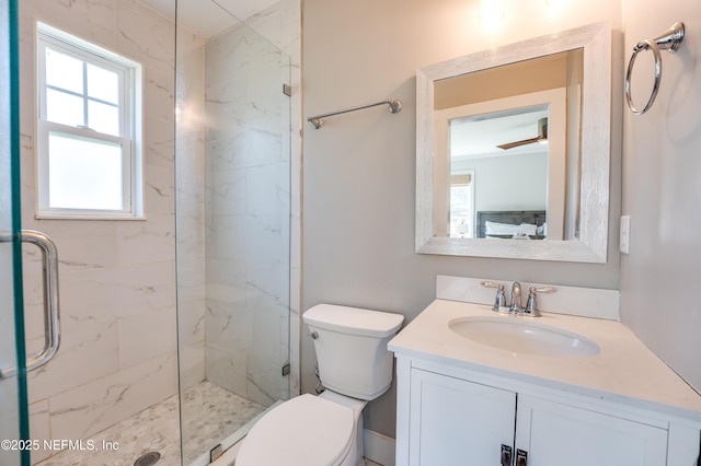 bathroom featuring toilet, a marble finish shower, and vanity