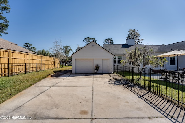 view of side of property featuring an outbuilding, concrete driveway, a lawn, fence, and a garage