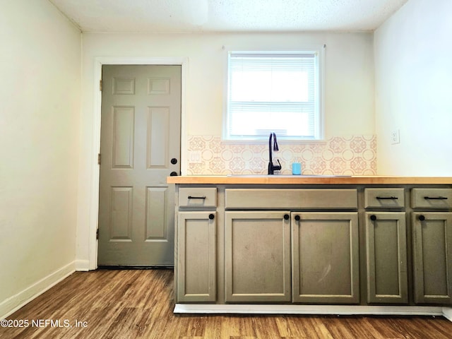 interior space featuring dark wood finished floors, a sink, backsplash, and baseboards