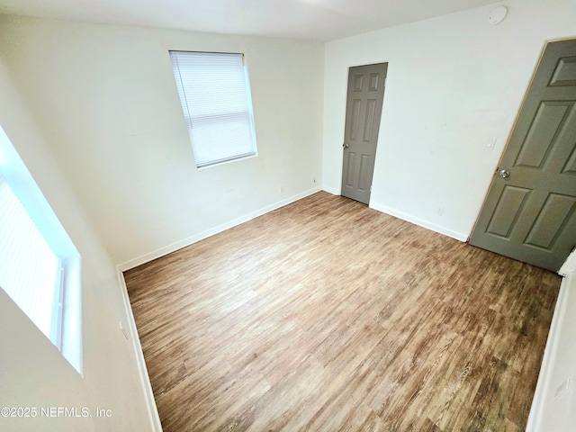 unfurnished room featuring a wealth of natural light, baseboards, and wood finished floors