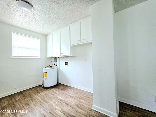 washroom with light wood-style floors, water heater, and a textured ceiling