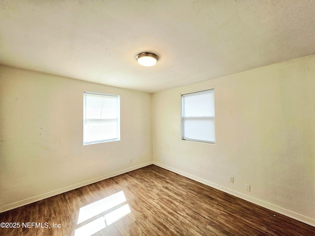 spare room with baseboards and wood finished floors