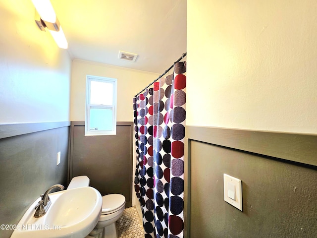 full bathroom with visible vents, toilet, a wainscoted wall, crown molding, and a sink