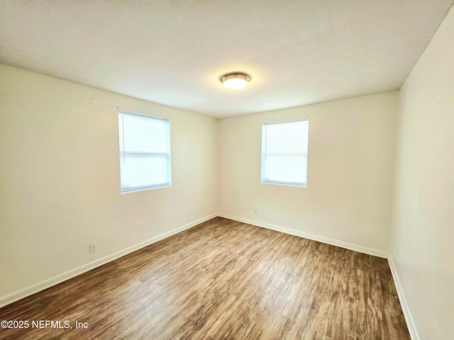 spare room with baseboards and wood finished floors