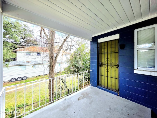 doorway to property with a lawn, concrete block siding, and a balcony