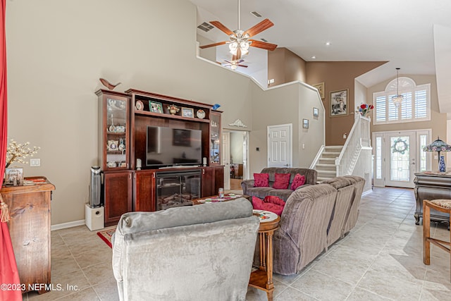 living room with stairway, light tile patterned floors, baseboards, visible vents, and high vaulted ceiling
