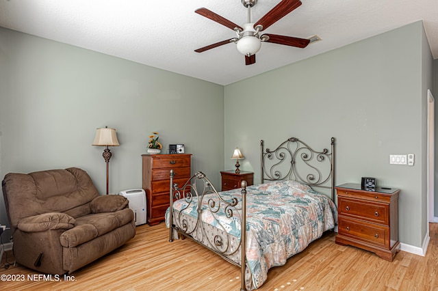 bedroom with visible vents, baseboards, a ceiling fan, and wood finished floors
