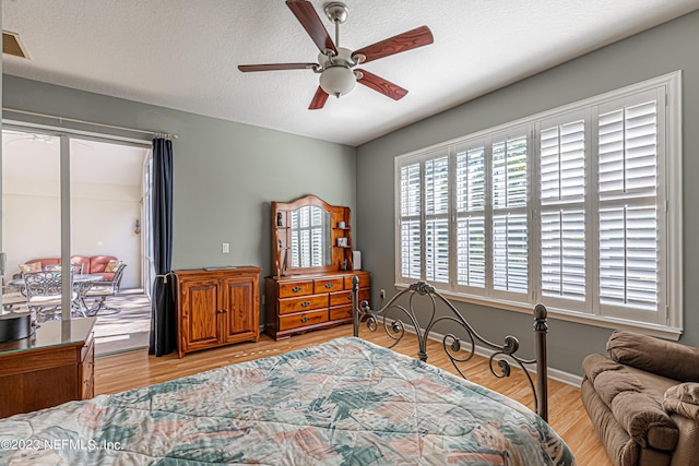 bedroom with access to exterior, a textured ceiling, light wood-style floors, baseboards, and ceiling fan