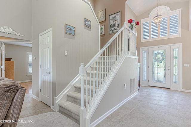 tiled foyer featuring visible vents, high vaulted ceiling, a healthy amount of sunlight, and stairway