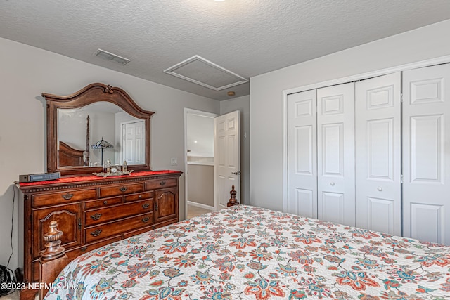 bedroom with a closet, visible vents, a textured ceiling, and attic access