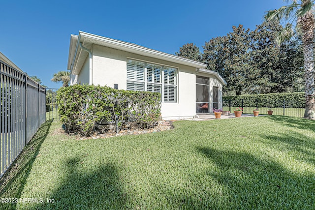 back of house featuring a yard, a sunroom, a fenced backyard, and stucco siding