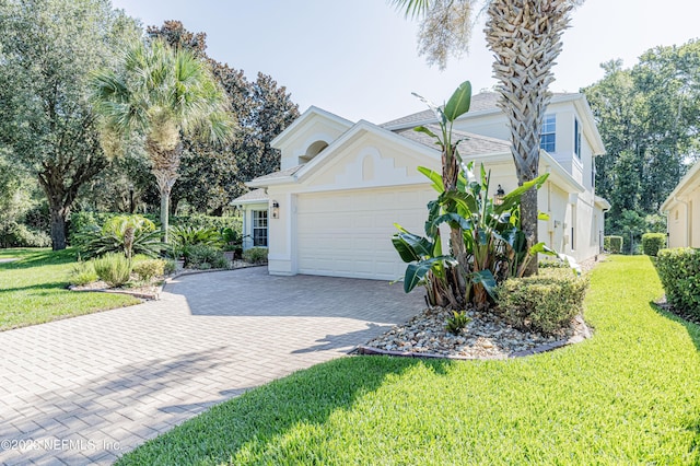 view of front of property with decorative driveway, a front lawn, an attached garage, and stucco siding