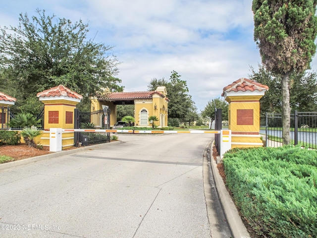 view of road with curbs, a gated entry, and a gate
