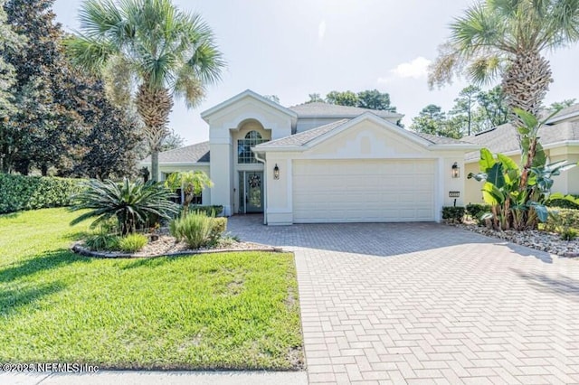 view of front of home featuring decorative driveway, a garage, a front lawn, and stucco siding