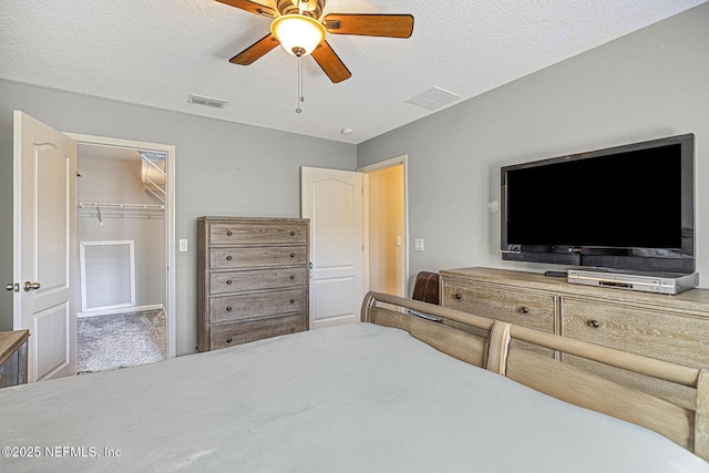 bedroom featuring carpet, a spacious closet, visible vents, and a textured ceiling