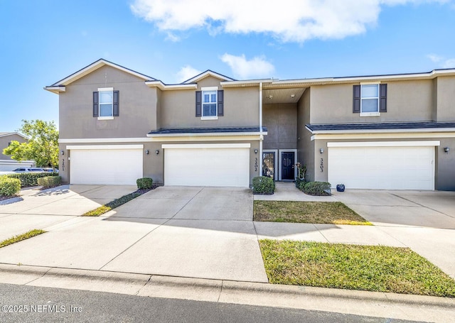 view of front facade featuring concrete driveway, an attached garage, and stucco siding