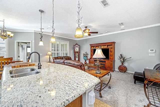 kitchen featuring decorative light fixtures, a sink, visible vents, and light colored carpet