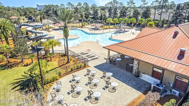 pool with a lawn, a patio area, fence, a water slide, and a fire pit