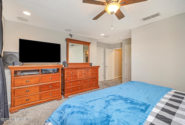 carpeted bedroom featuring ceiling fan, visible vents, and a textured ceiling