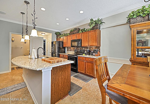 kitchen with a center island with sink, ornamental molding, brown cabinets, black appliances, and a sink